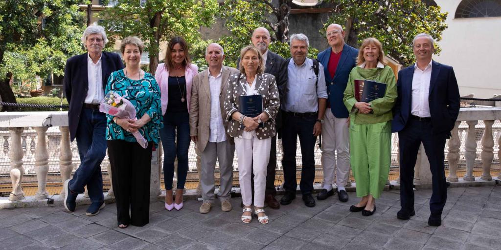 studenti unigesenior felici che tengono in mano le loro tesi con alberi nello sfondo